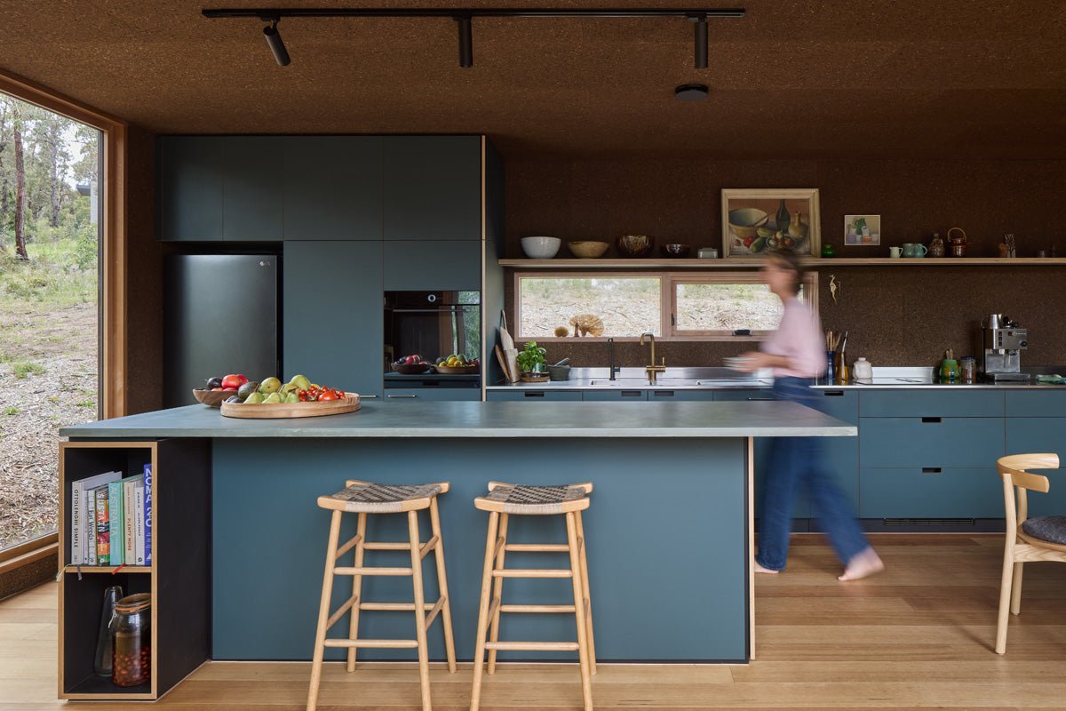 Modern kitchen with blue cabinets and a person walking past the window